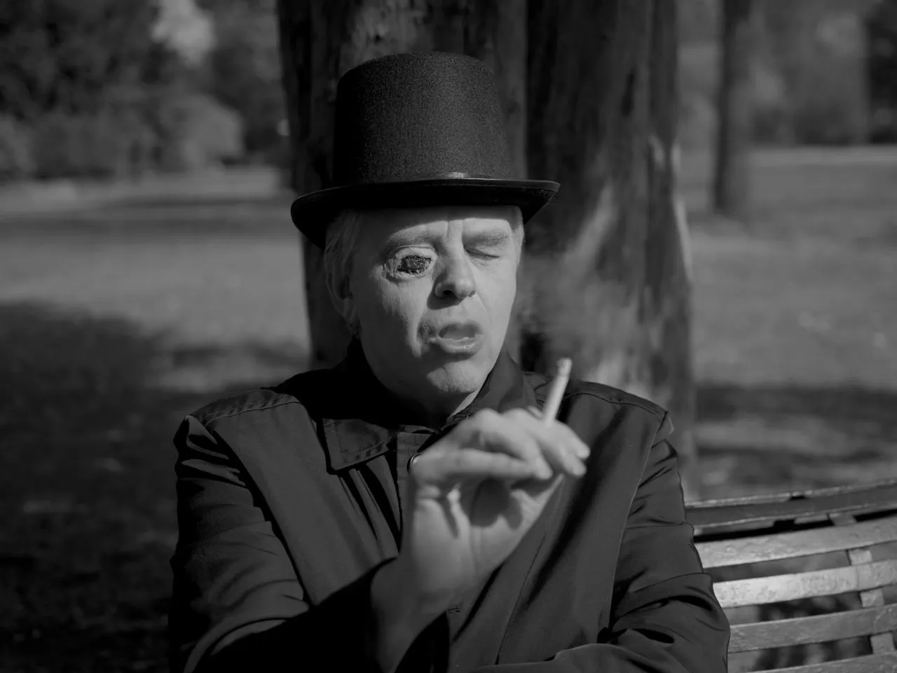 Black-and-white close-up of a person in a top hat holding a cigarette.