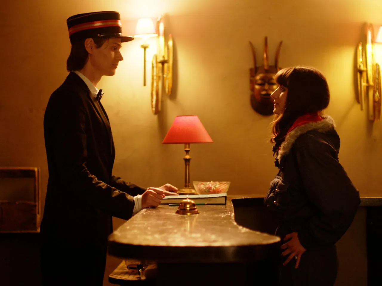 Uniformed attendant and a guest facing each other across a hotel counter.