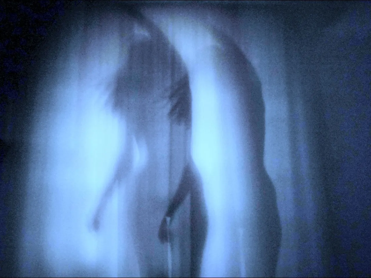 Blurred blue-lit figure behind a translucent surface.