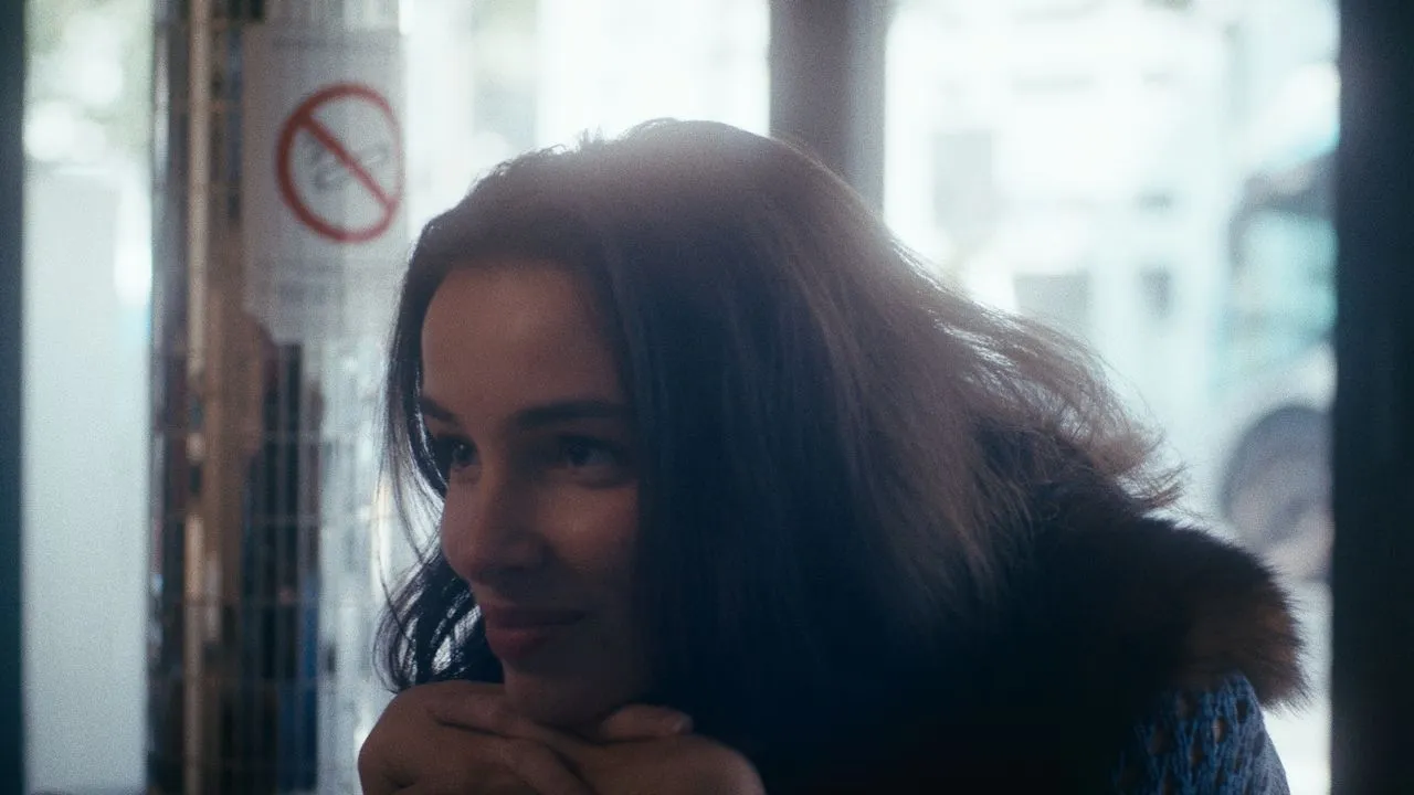 Person sitting by a cafe window with their chin resting on their hand.